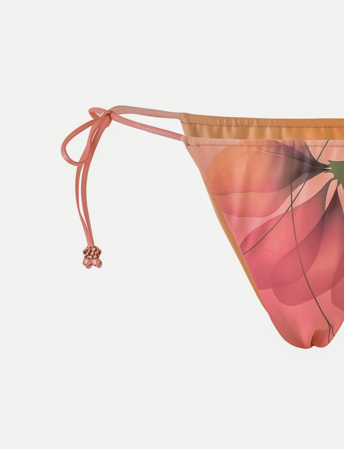 Close-up of the TIGERMIST AVE BIKINI BOTTOM - PINK : MACRO FLORAL, featuring adjustable side ties with pink bead details. The macro floral pattern stands out against a plain white background.