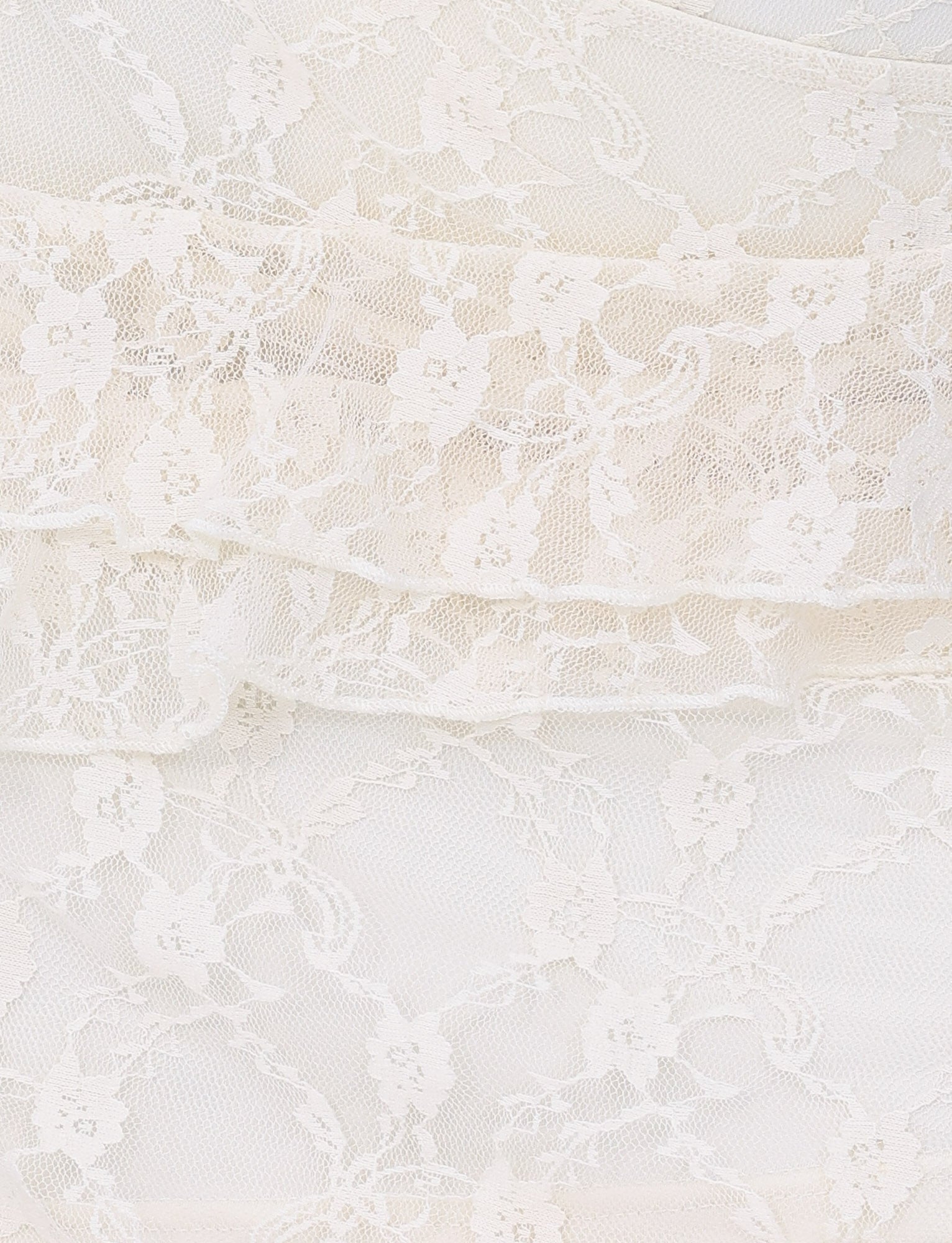 A close-up of delicate white lace fabric, featuring an intricate floral pattern and layered stretch lace, mirrors the elegant texture of the TIGERMIST Stormi Lace Skirt in Beige Champagne with Champagne Lace.
