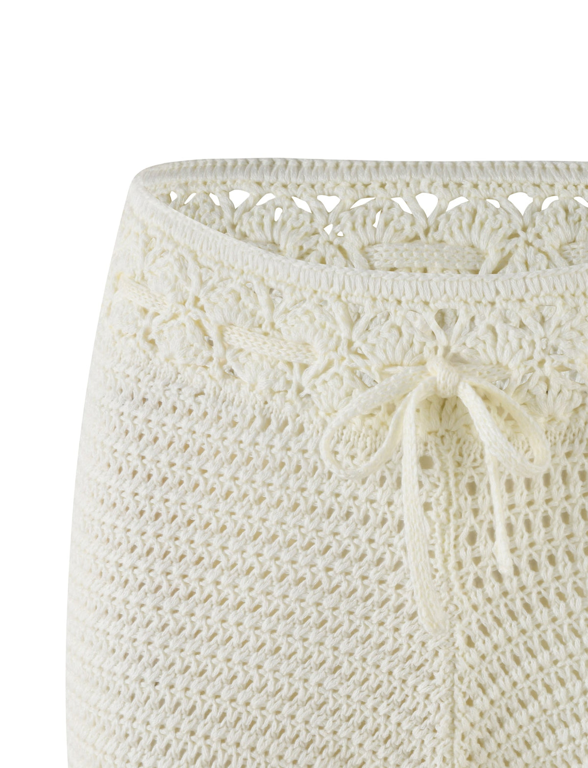 A close-up of the JONAS SHORT - WHITE : CREAM from TIGERMIST showcases intricate crochet patterns with a decorative knit tie at the mid-rise waist. The texture and weave details are prominently visible, highlighting the high stretch fabric's flexibility.