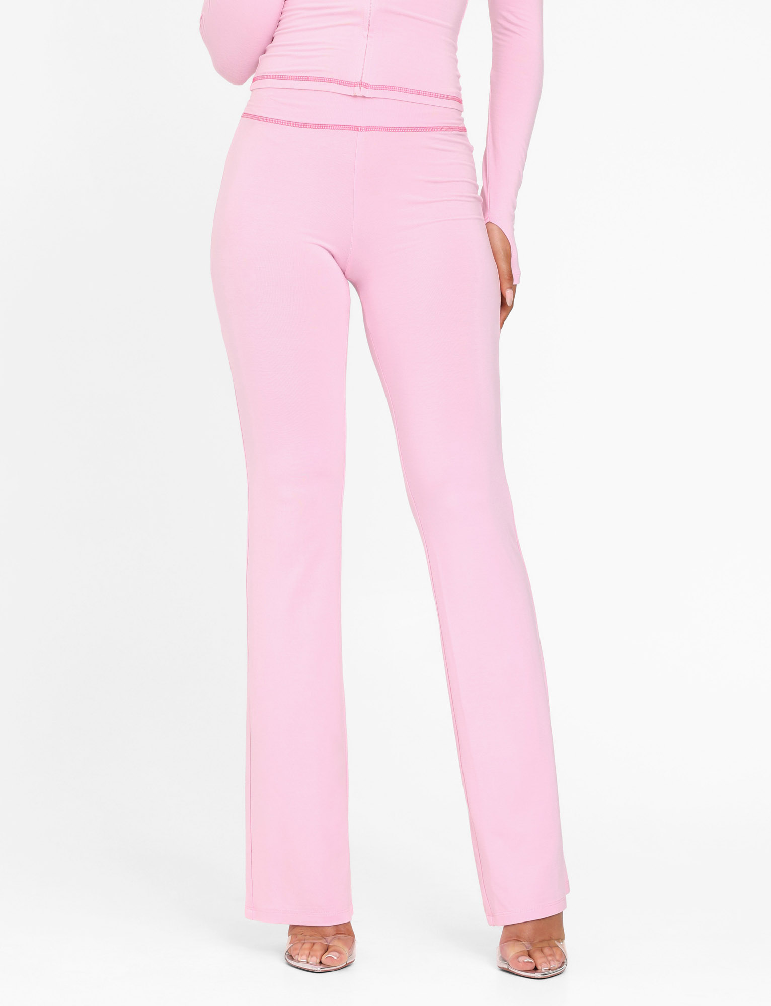 A person wearing TIGERMIST's BLAYZE PANT in soft pink with a matching long-sleeve top and clear open-toe heels, cropped from shoulders down against a white background.