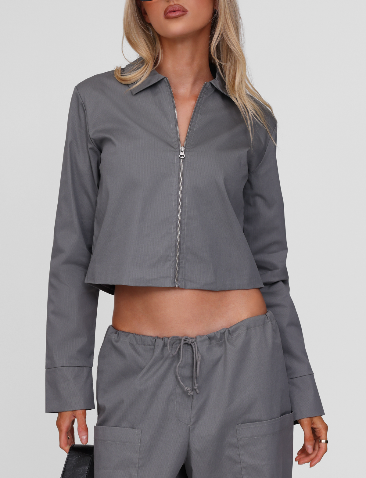 A woman models the TIGERMIST TYSHA JACKET in charcoal, featuring a boxy fit, paired with matching drawstring pants against a plain background.