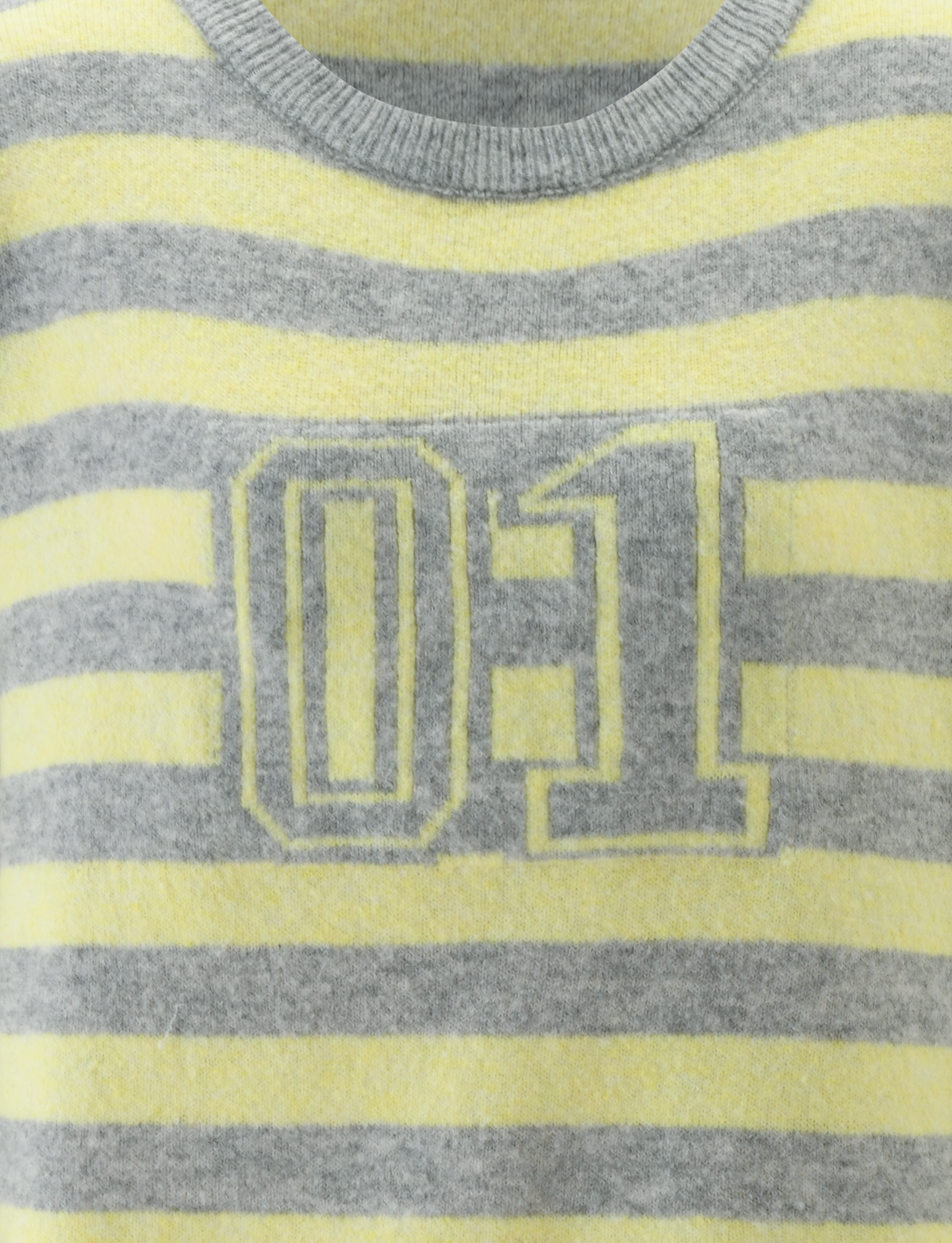A close-up of the TIGERMIST KOA JUMPER—an oversized knit sweater with horizontal yellow and grey stripes, featuring a sporty white-outlined "01" on the front.