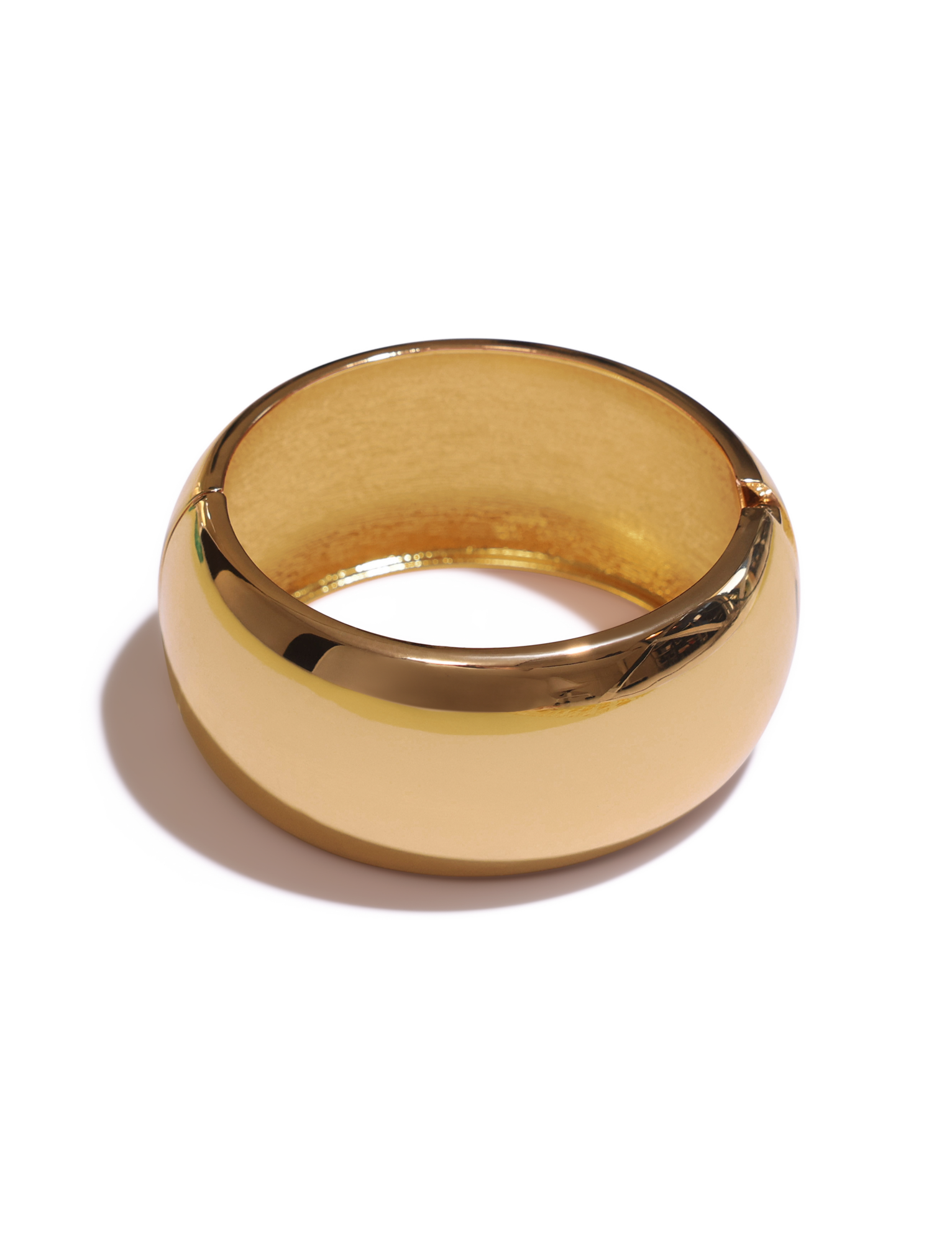 The TIGERMIST MIRAH CHUNKY BANGLE - GOLD features a wide, shiny gold design with a smooth, reflective surface, exuding bold elegance reminiscent of a chunky bracelet, beautifully displayed on a white background with a soft shadow.