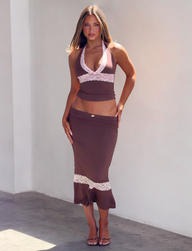 A person wearing a brown halter top with pink lace detail and the matching CALINA LACE PANEL MIDI SKIRT - CHOCOLATE in a mermaid silhouette with a pink lace hem panel.