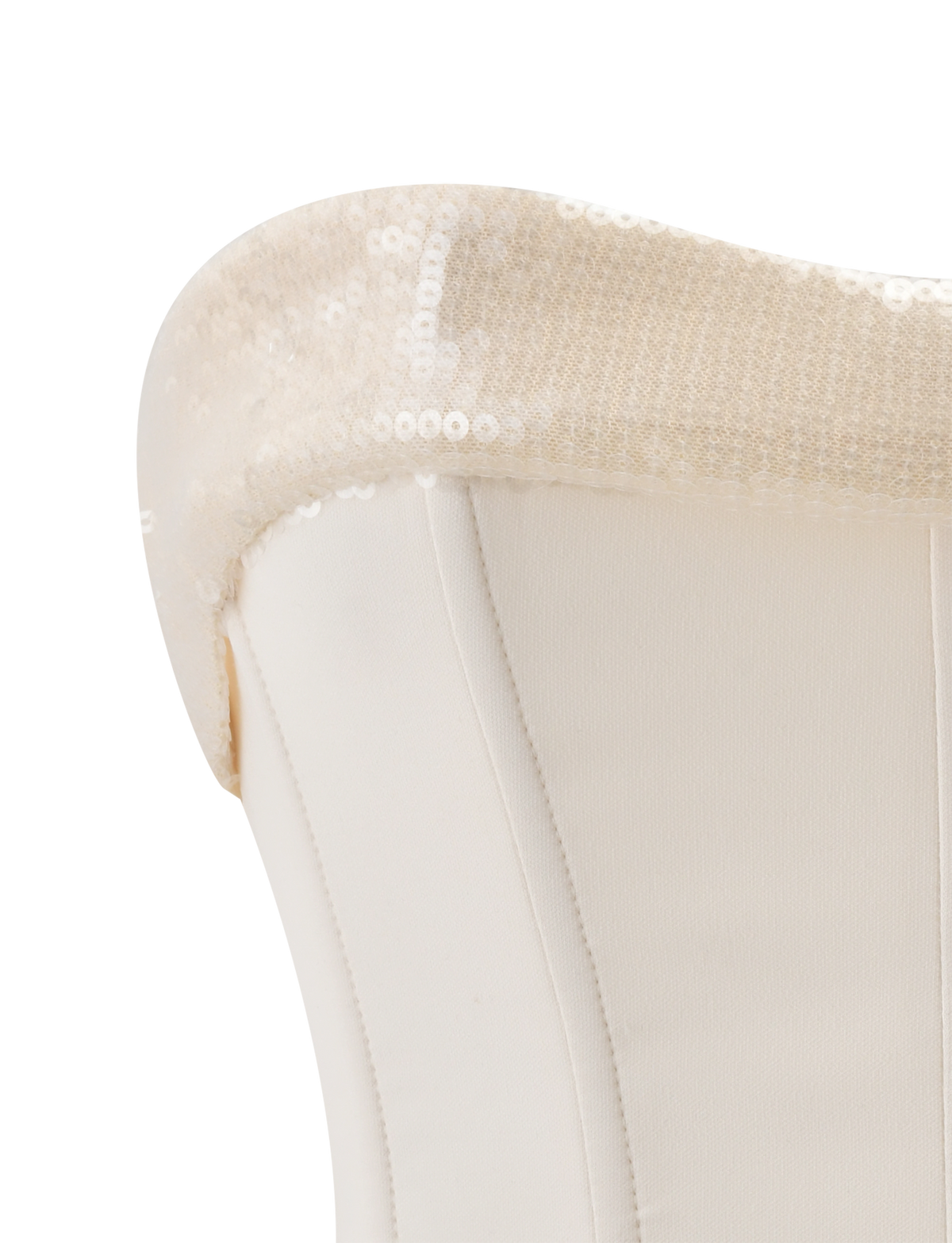 Close-up of a white upholstered chair's backrest adorned with the TIGERMIST CHARLYZE BUSTIER in cream, its sequined details draped elegantly over the top edge, evoking the refined style of a corset bustier.