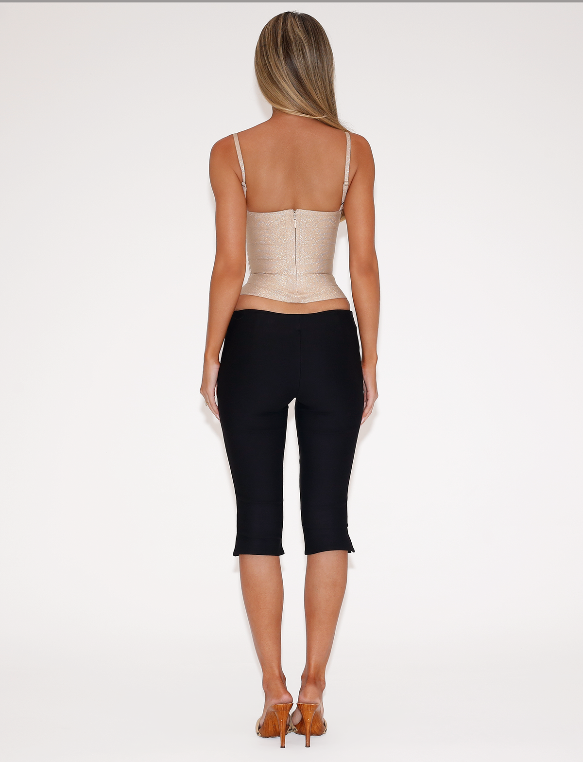 Back view of a person wearing a beige corset top and MOLLIE CAPRI - BLACK pants with heeled sandals.
