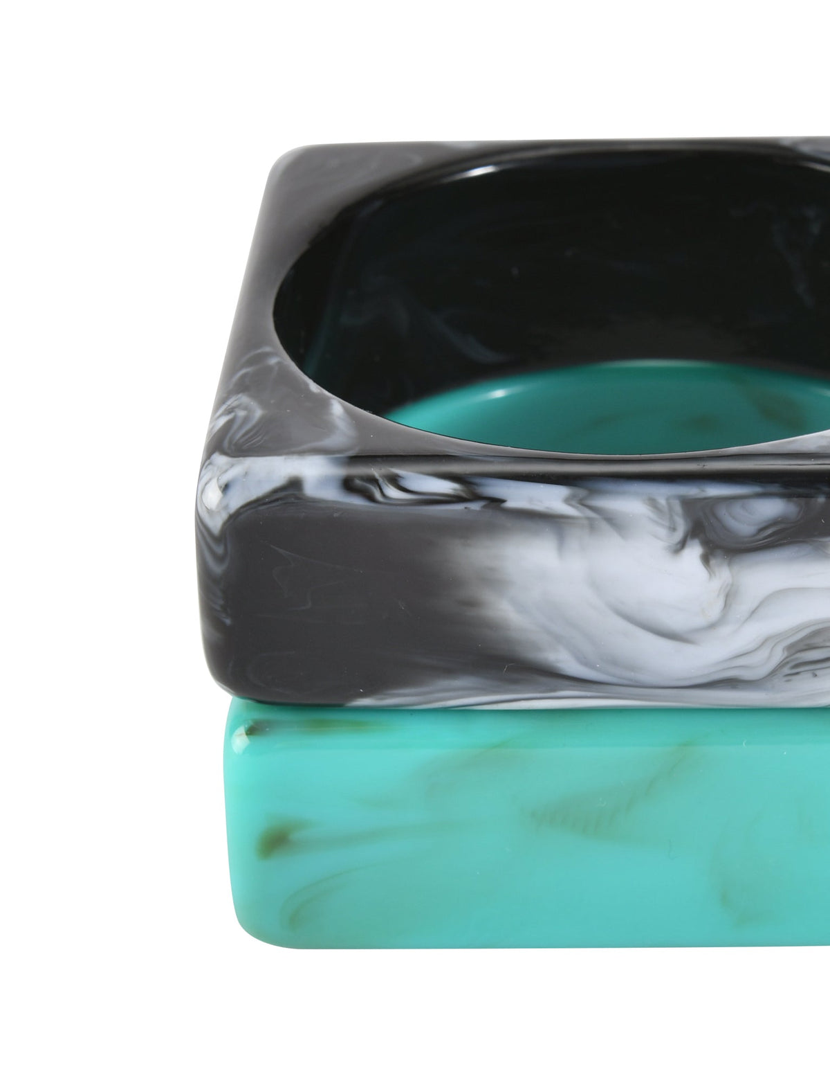 Two square resin bangles from TIGERMIST, the AUGIE BANGLE SET - EMERALD AND BLACK: one with a black-and-white marble effect, the other turquoise with green swirls. Both have rounded edges and glossy surfaces.