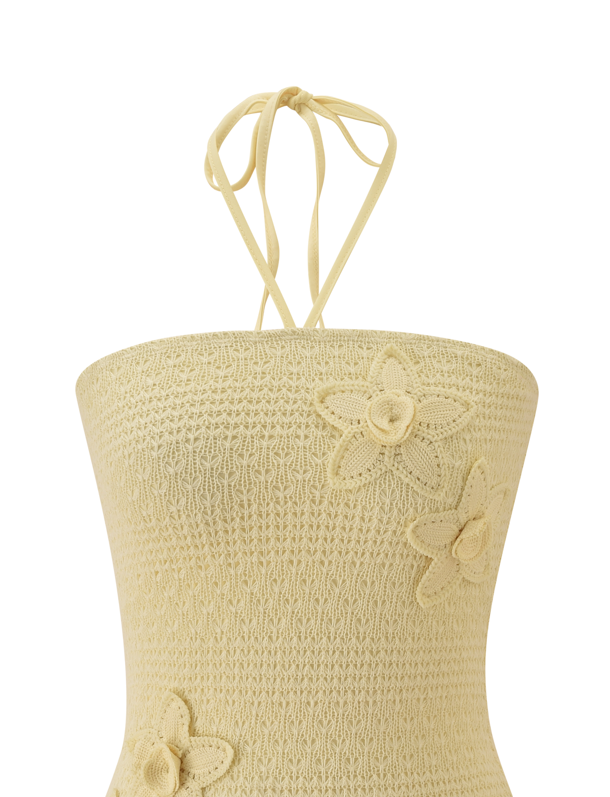 The KORRI DRESS - BUTTER by TIGERMIST features delicate crochet details and a soft beige hue, with thin neck ties and floral appliques adding texture and charm to the front.