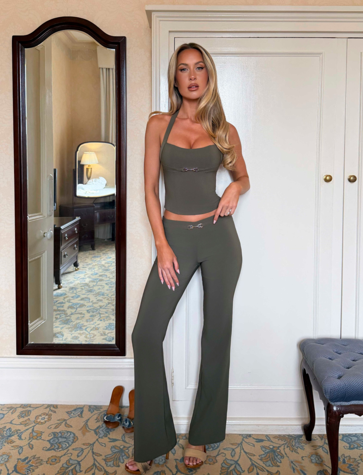 A woman wears an olive green halter-neck corset top with a silver buckle detail and matching high-waisted KITTIE BUCKLE PANT - OLIVE trousers.