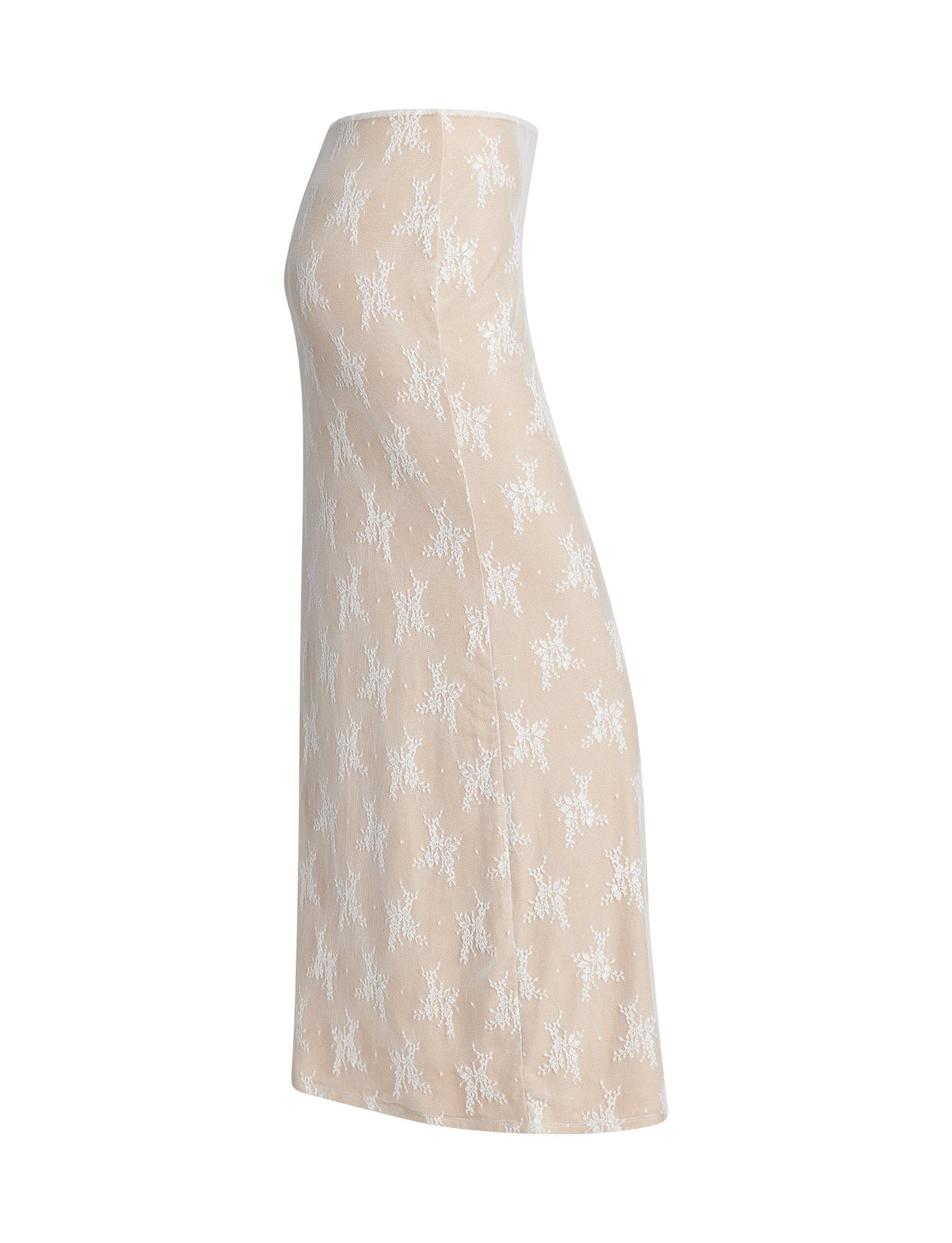 A beige midi skirt named "KAROLINA SKIRT - WHITE : WHITE LACE" from TIGERMIST, featuring a white floral lace overlay, displayed on a white background. The skirt has a fitted style and falls straight down to the mid-calf. The intricate lace details create a delicate pattern across the fabric.
