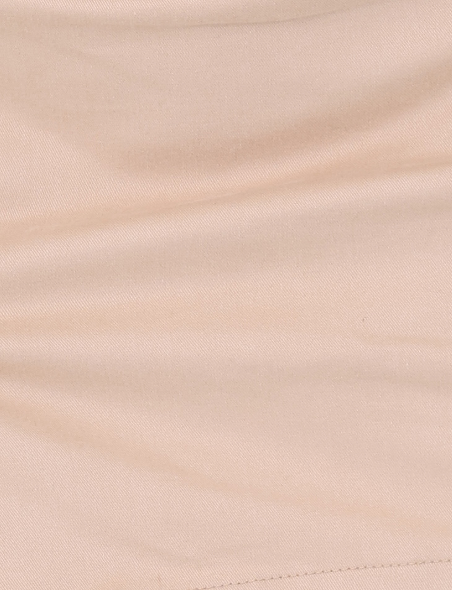 A close-up of smooth tan fabric with gentle folds, a subtle diagonal seam at the lower right, and the overlap waistband structure of the TIGERMIST KITTIE SKORT - TAN.