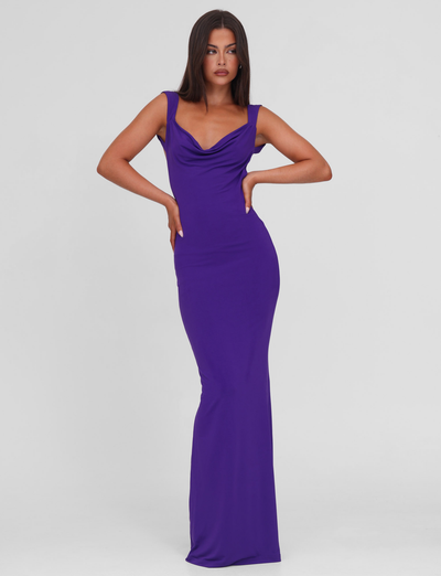 A woman poses confidently in the TIGERMIST ZITA MAXI DRESS - PURPLE, a sleeveless, bodycon, floor-length dress with a scoop cowl neck, standing against a plain white background.