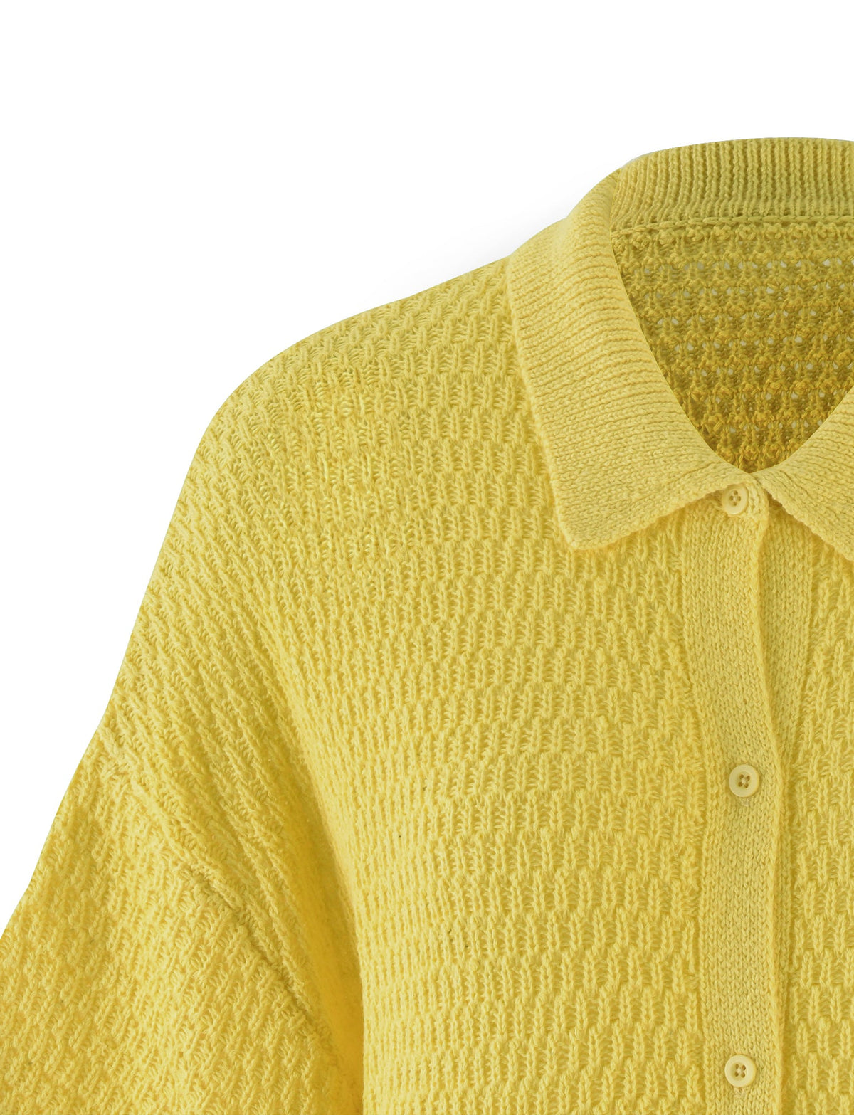 A close-up image of the JANAI TOP in LEMON by TIGERMIST. This yellow knit cardigan features a ribbed collar, matching yellow buttons along the button-up front, and a woven pattern throughout the fabric. The visible sleeve seam indicates a loose fit design.
