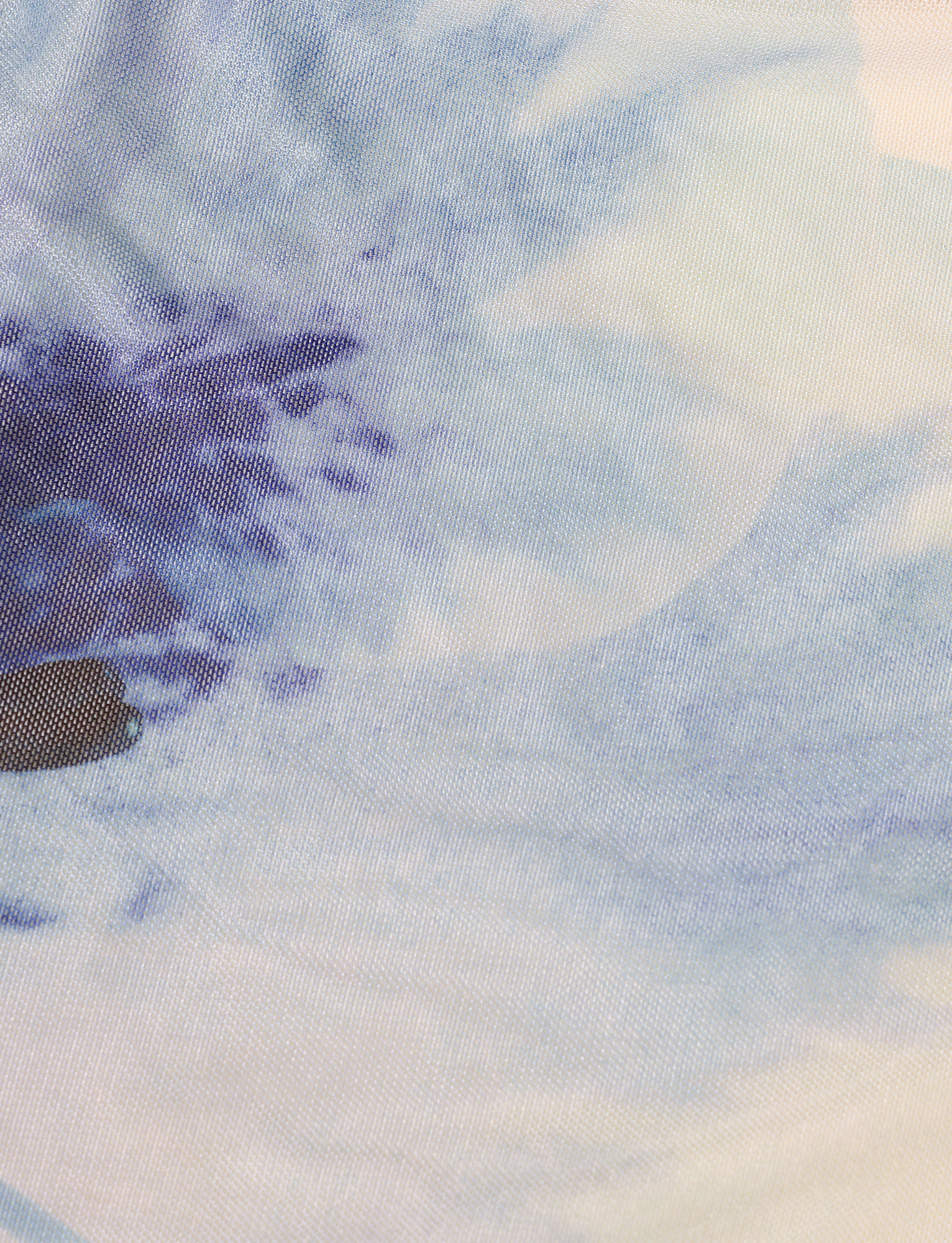 Close-up of the LILLIAN TOP by TIGERMIST in white and cream, featuring a blue floral print with soft, cloud-like shapes and subtle gradient transitions in an abstract pattern.