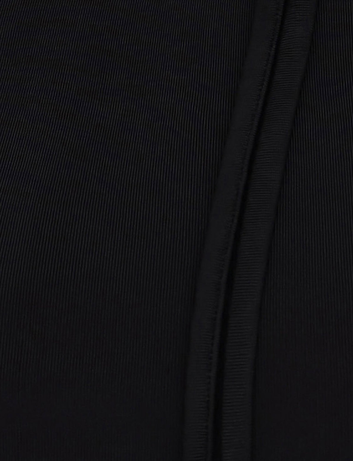 Close-up of a TIGERMIST MIETTA TOP - BLACK showcasing its textured fabric and a vertical seam on the right side. The high-stretch, ribbed material gives it a subtly striped appearance, while the multi-tie neck adds an elegant finishing touch.