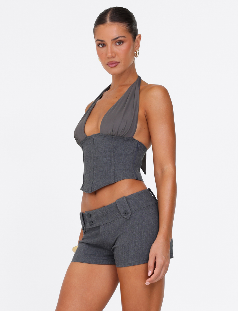 A woman with dark hair tied back wears the TIGERMIST KITTIE SHORT - GREY and a matching gray halter top, posing against a plain white background.