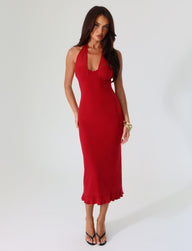 A person with long dark hair is wearing the TIGERMIST GRANGER MIDI DRESS in cherry red, featuring a sleeveless, halter-neck design with a ruffled hem. They are standing against a plain white background and are accessorized with black high-heeled sandals and a gold bracelet.