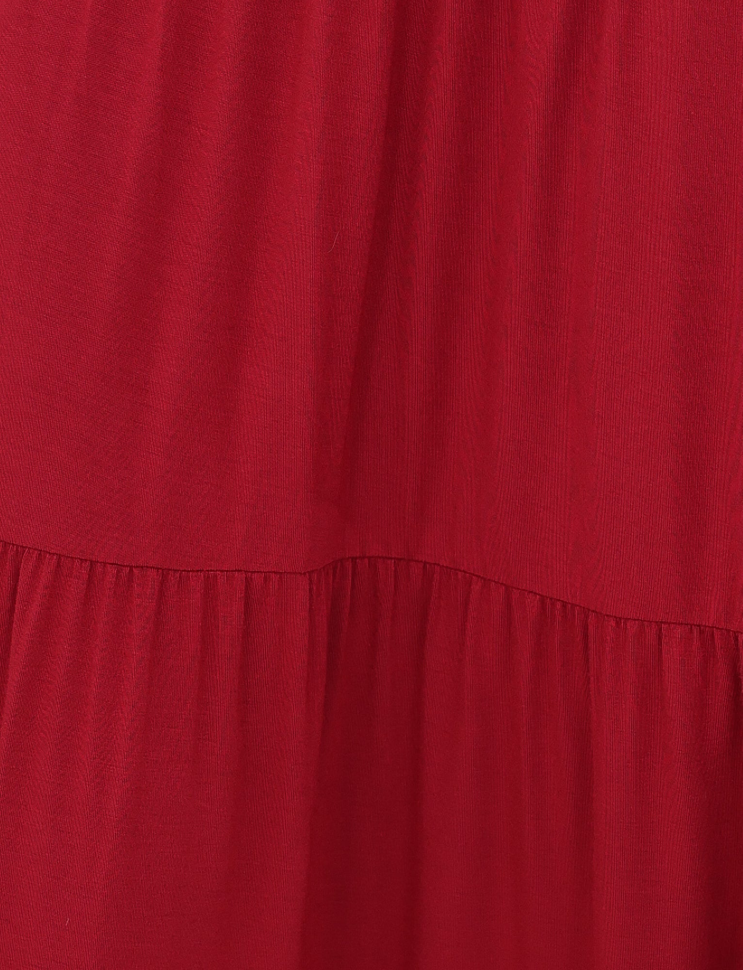 Close-up of the KATYA MAXI SKIRT in red by TIGERMIST reveals its lightweight fabric and gathered texture; tiered panels add a subtle layered depth to the garment.