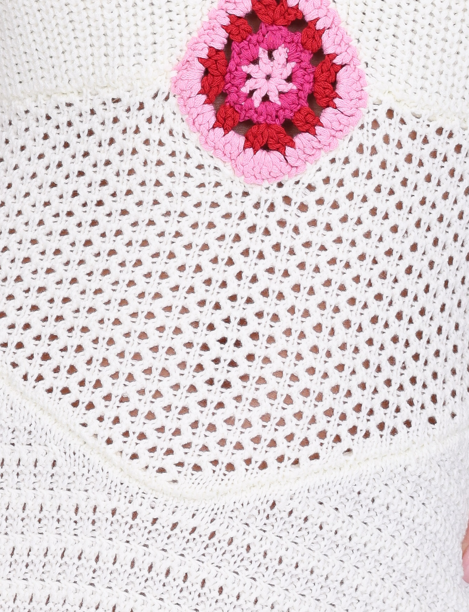 A close-up of the TIGERMIST TENZIN MINI DRESS in cream, featuring white crochet fabric with an open mesh-like pattern and a pink, red, and white Granny Square detail near the top.
