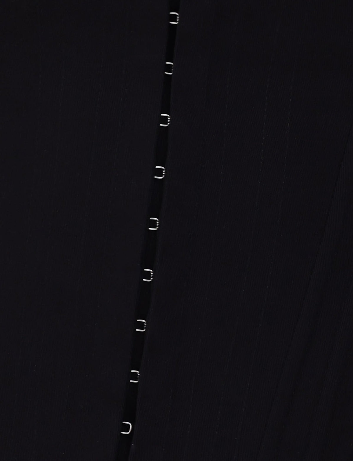 Close-up of the TIGERMIST "MILLIE CORSET 2.0 - BLACK" featuring a vertical row of small silver hooks. The black denim fabric showcases subtle diagonal parallel lines, adding a textured element to the material. The evenly spaced silver hooks create a sleek and minimalist pattern.