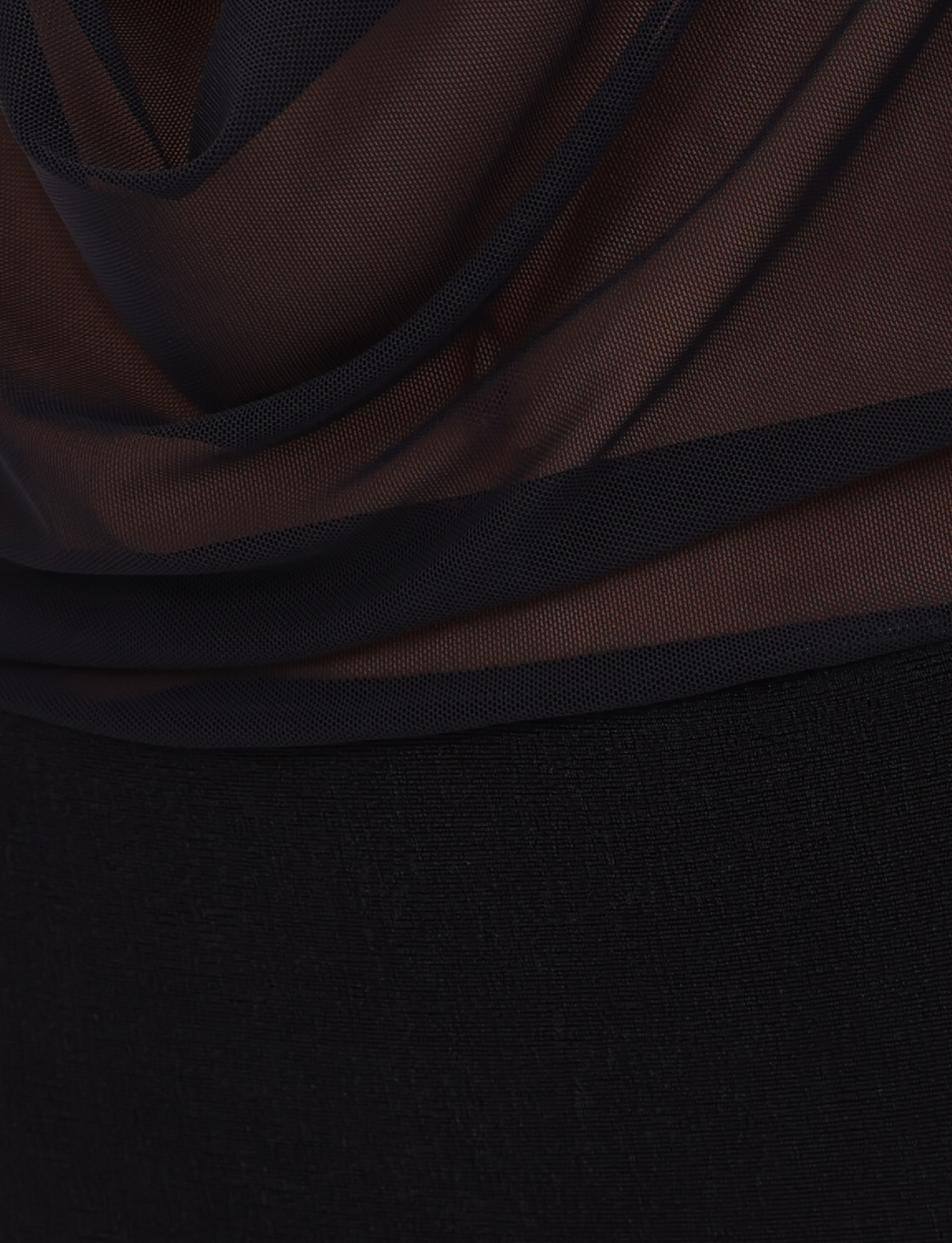 A close-up of sheer black fabric draped over textured material, with soft folds and light filtering through—evoking the delicate layers of the TIGERMIST MAKENA TWO-PIECE DRESS in black.