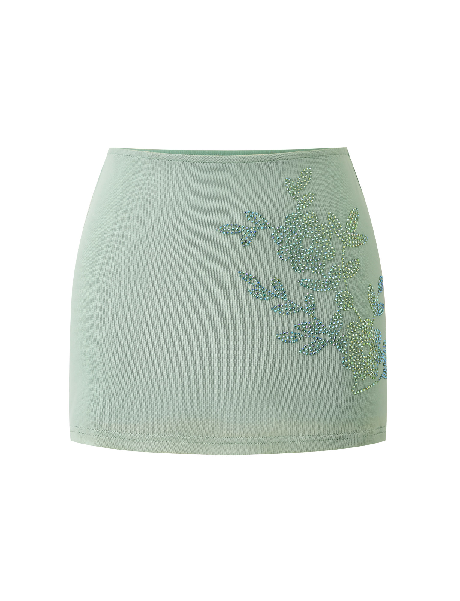 The OCTAVIA MINI SKIRT in pistachio by TIGERMIST features a light green hue and rhinestone floral embellishment on one side, showcased against a plain white background.