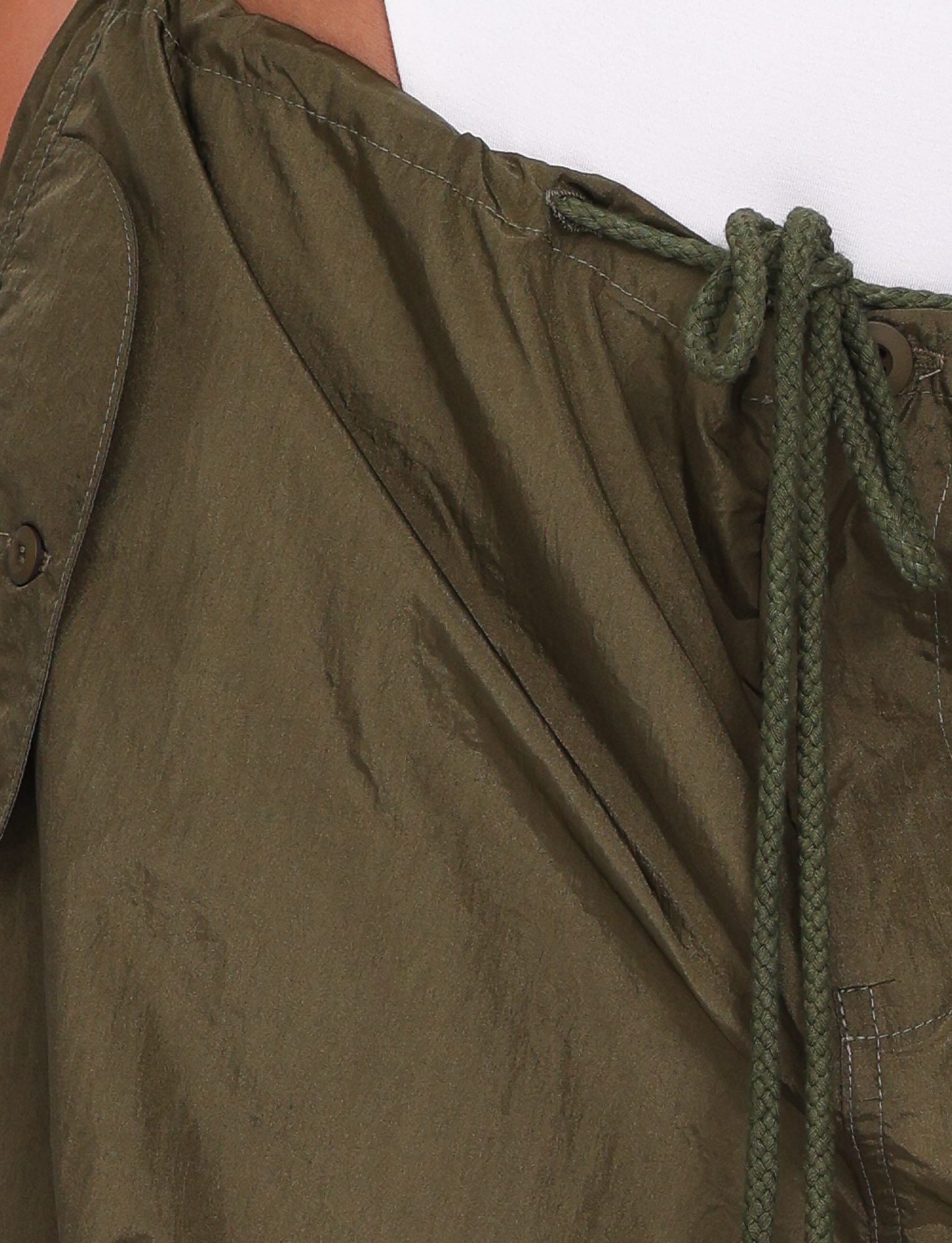 Close-up of the TIGERMIST VIOLETTE PANT in khaki green nylon, featuring an adjustable drawcord waist with detailed stitching and a button detail, shown tied neatly at the top edge near a tan surface.