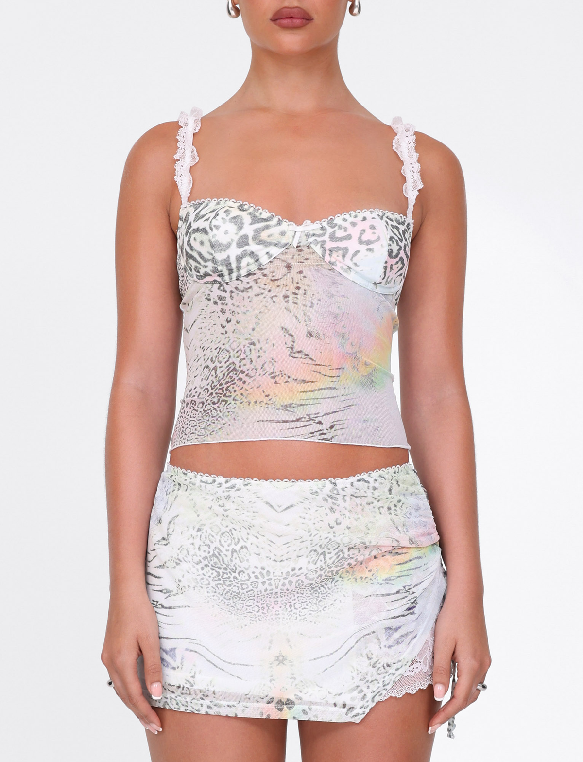 A woman wears the TIGERMIST JOSEPHINE MINI SKIRT in white animal print with ruched sides, paired with a matching lace-trim camisole. The background is plain white.