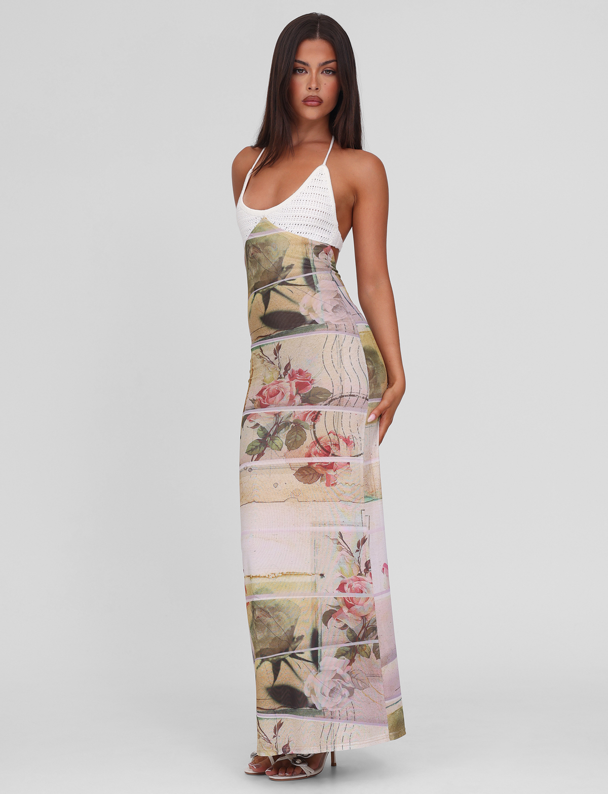 A woman with long, straight dark hair and neutral makeup poses against a white background, wearing the TIGERMIST TILLEY MAXI DRESS - ROSE POSTCARD, featuring printed mesh, crochet bust cups, and a floral print skirt.