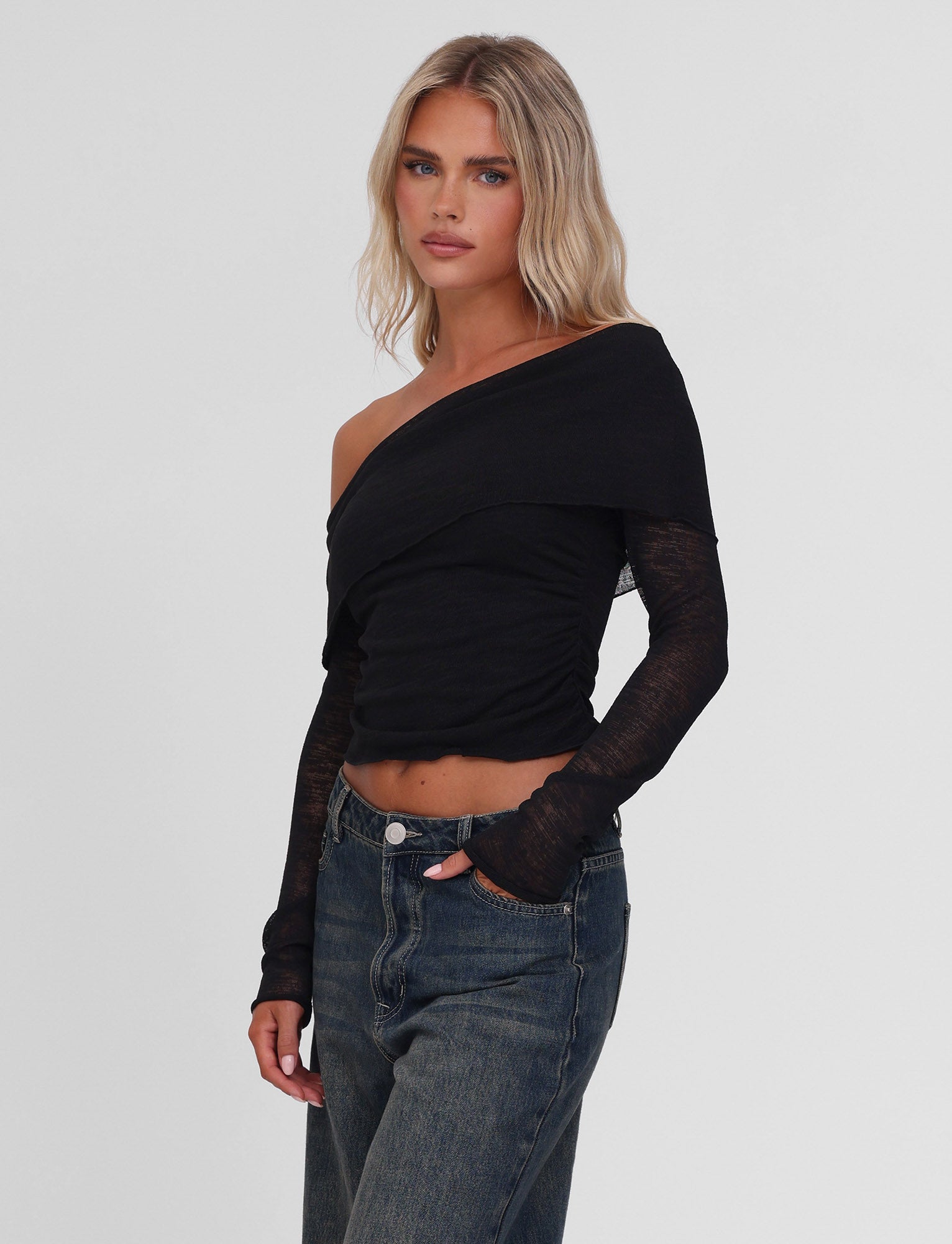 A woman with long blonde hair models the TIGERMIST VERA TOP in black, paired with high-waisted blue jeans, against a plain white background.