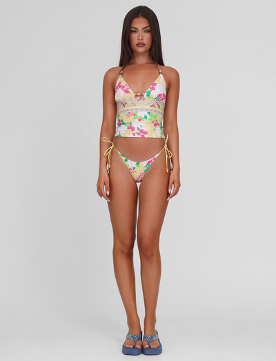 A woman with long brown hair stands against a plain background, wearing the TIGERMIST FINLEA TANKINI TOP in paisley border print and blue platform sandals. She faces forward with a neutral expression.