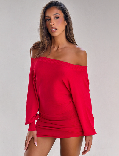 A woman wearing the TIGERMIST JANINE MINI DRESS in red stands against a light gray background, confidently facing the camera with one hand by her side.