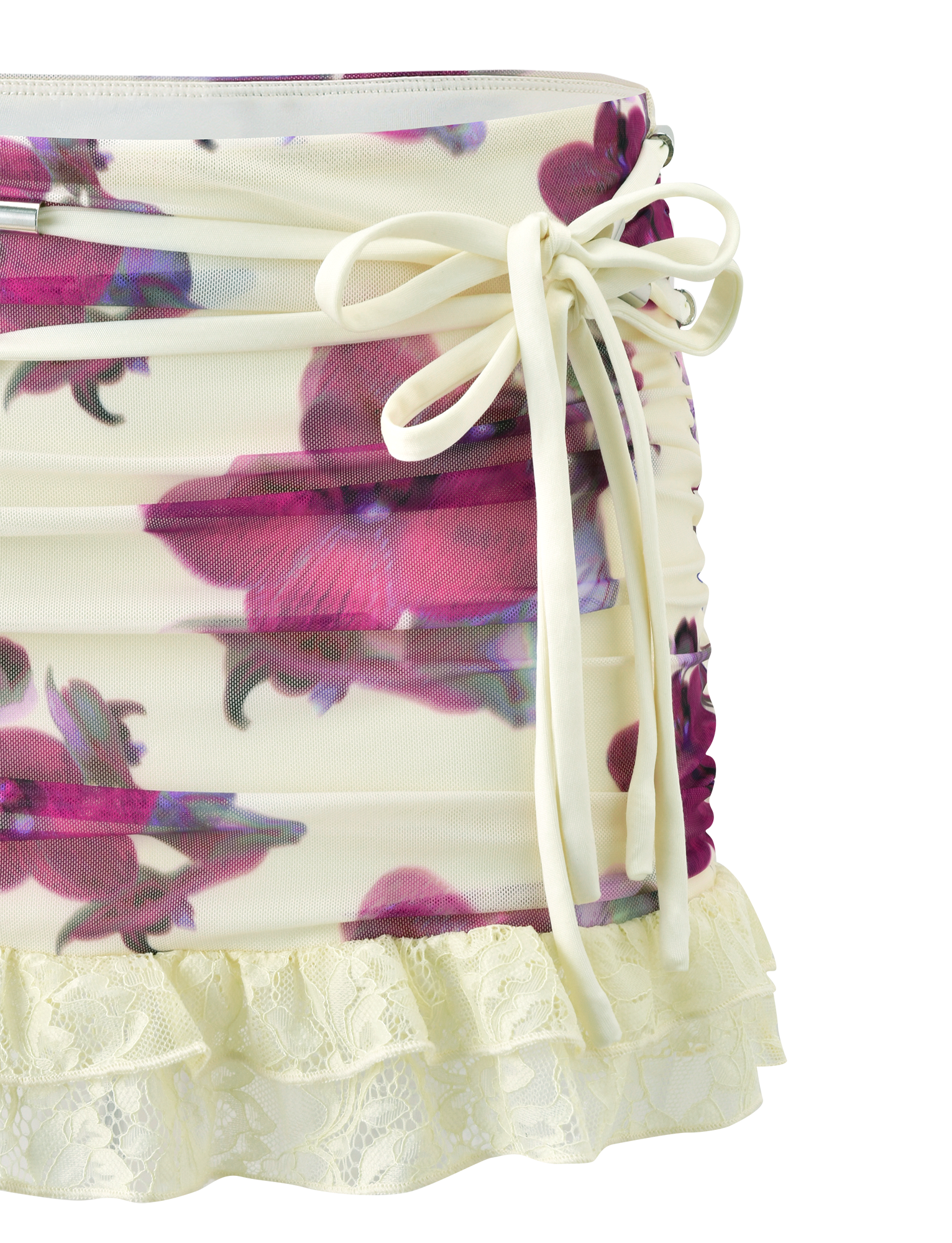 Close-up of TIGERMIST’s LILIAH MINI SKIRT in Orchid Haze, a cream floral mesh mini with vivid purple orchid print, ruched sides, side bow detail, and lace ruffle hem trim.