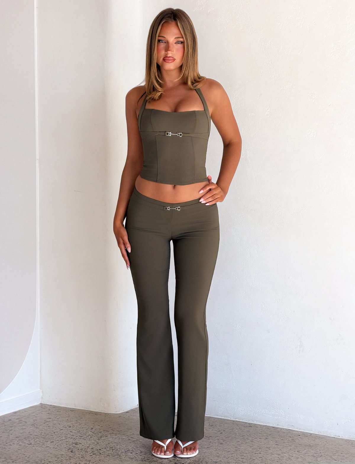 Olive green KITTIE BUCKLE PANT - OLIVE halter top and matching low-rise flared pants, both featuring silver metal buckle detail at the center.
