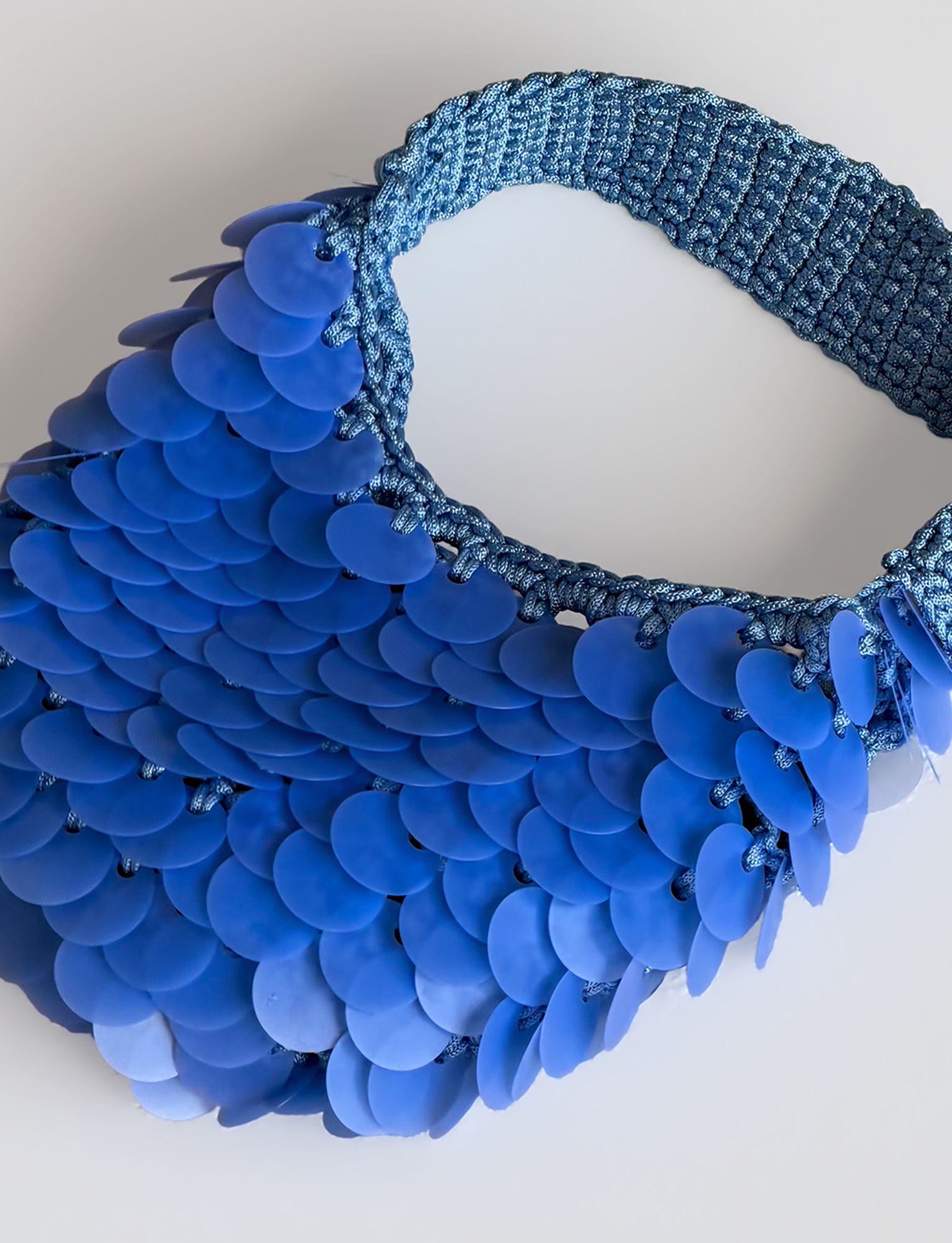 The TIGERMIST CLEO BAG in bright blue features a sequin crochet design with a woven strap and large, overlapping blue discs resembling fish scales, displayed against a light background.
