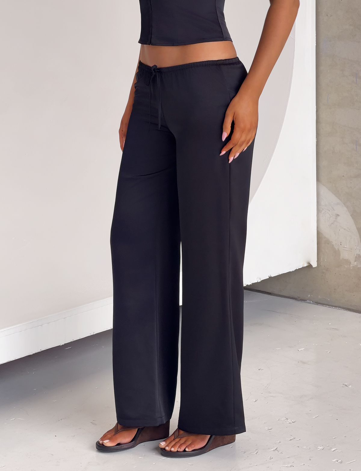 TIGERMIST MAURA PANT in black satin featuring an adjustable drawstring waist, wide-leg cut, paired with a matching sleeveless top and dark wedge sandals.